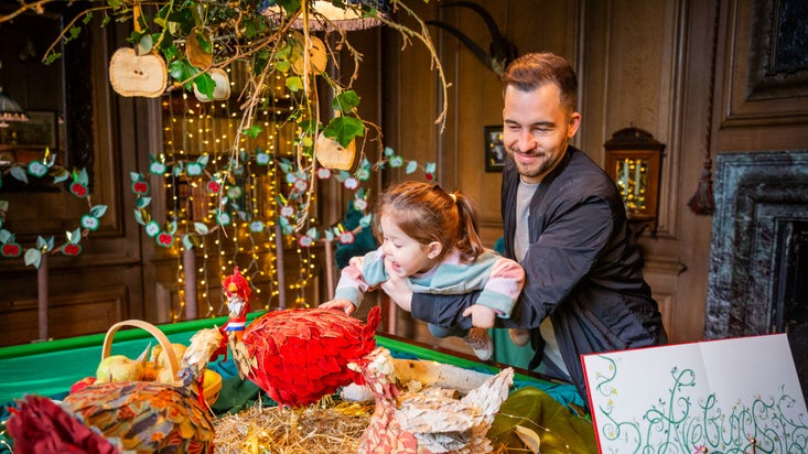 A father holding his daughter over a table so she can clearly look at the Christmassy display
